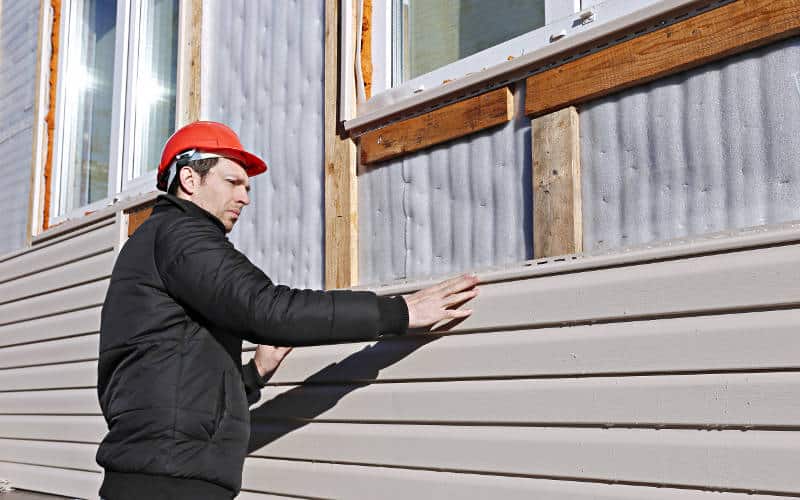 An Omaha siding professional installs panels beige siding on the facade of the house