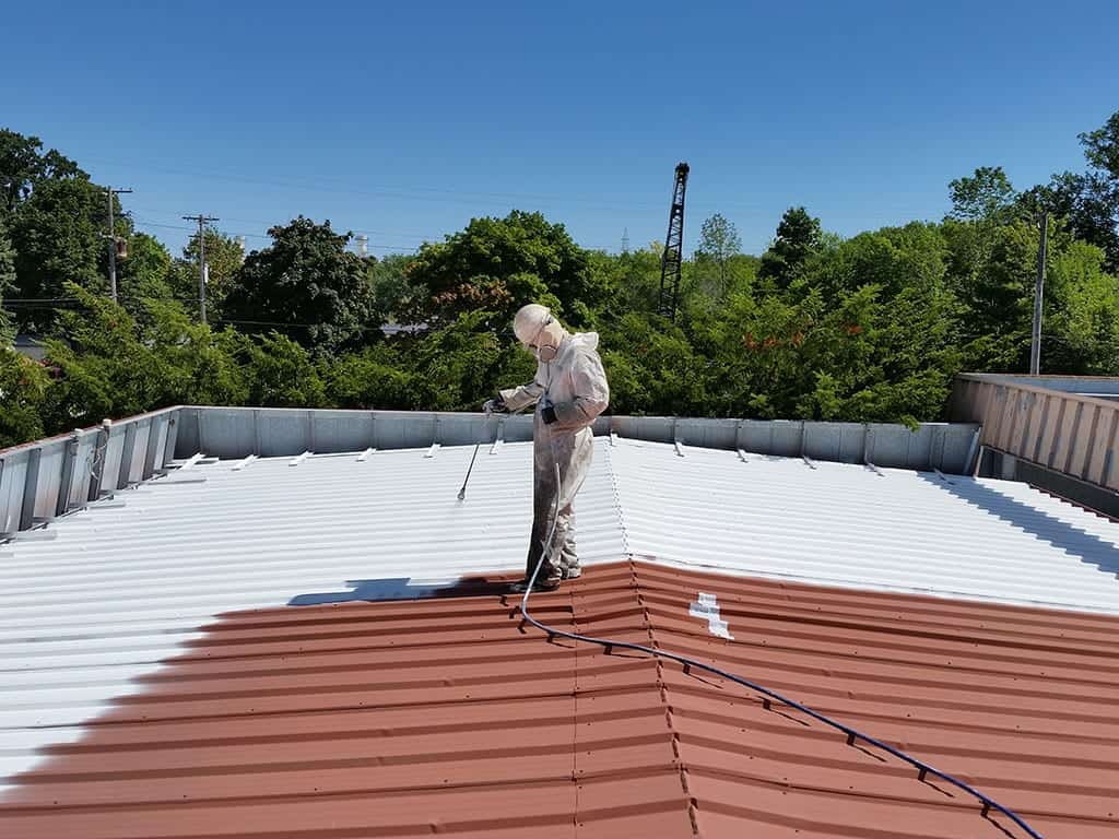 A guy coating a omaha commercial roof 
