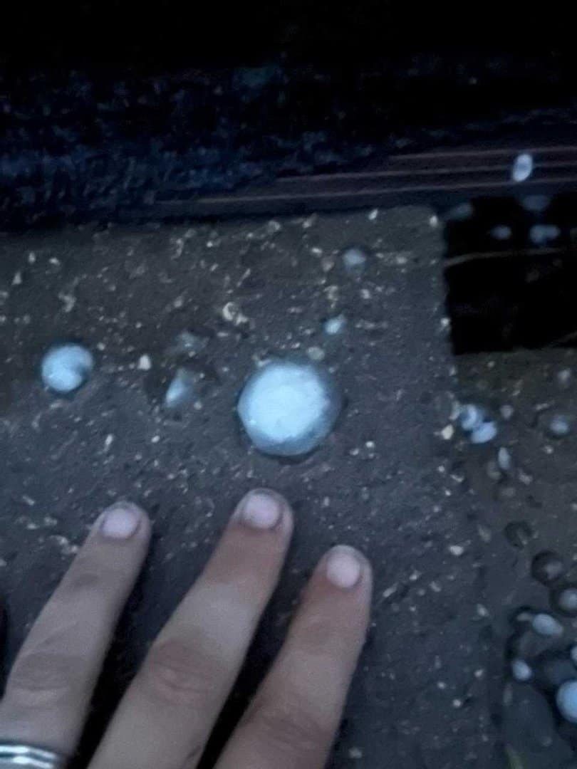 Hand pointing to piece of hail on Omaha roof