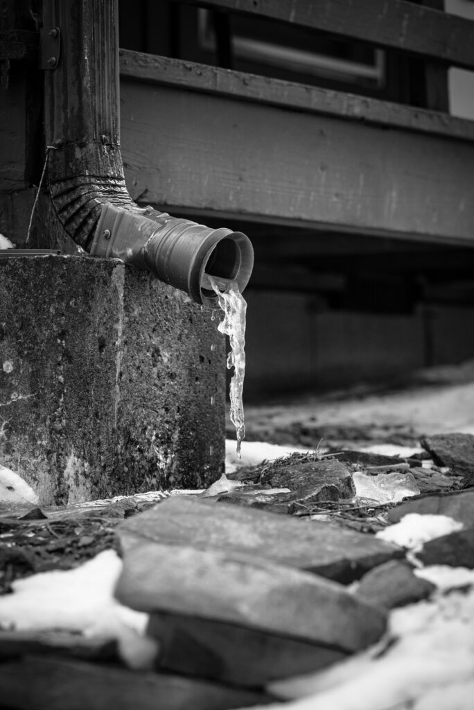 Black and white image of downspout end in Omaha gutter installation