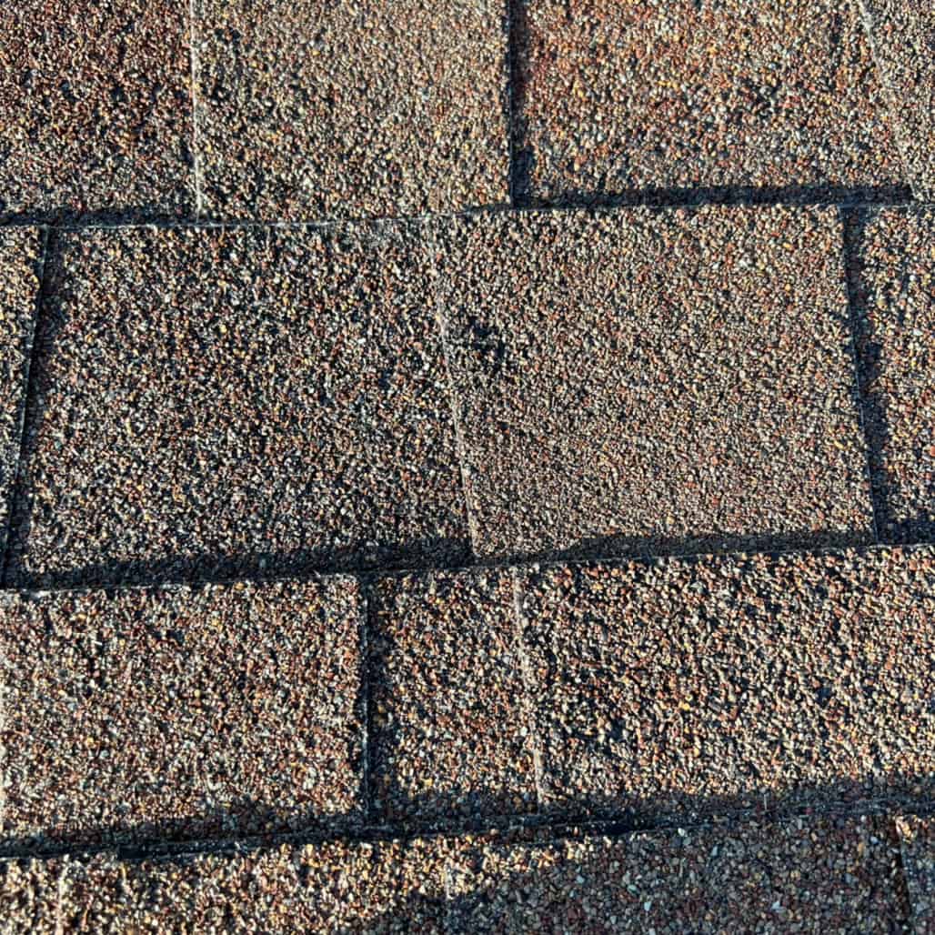 Close up of dent on asphalt roof shingle caused by recent Omaha hail storm