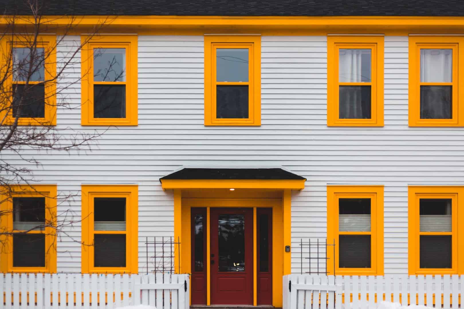 An Omaha home with white vinyl siding and yellow window shutters.