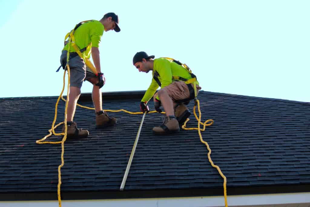 Two professional roofers repairing a roof.