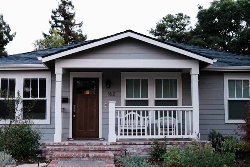 A grey Omaha home with a porch and grey vinyl siding.